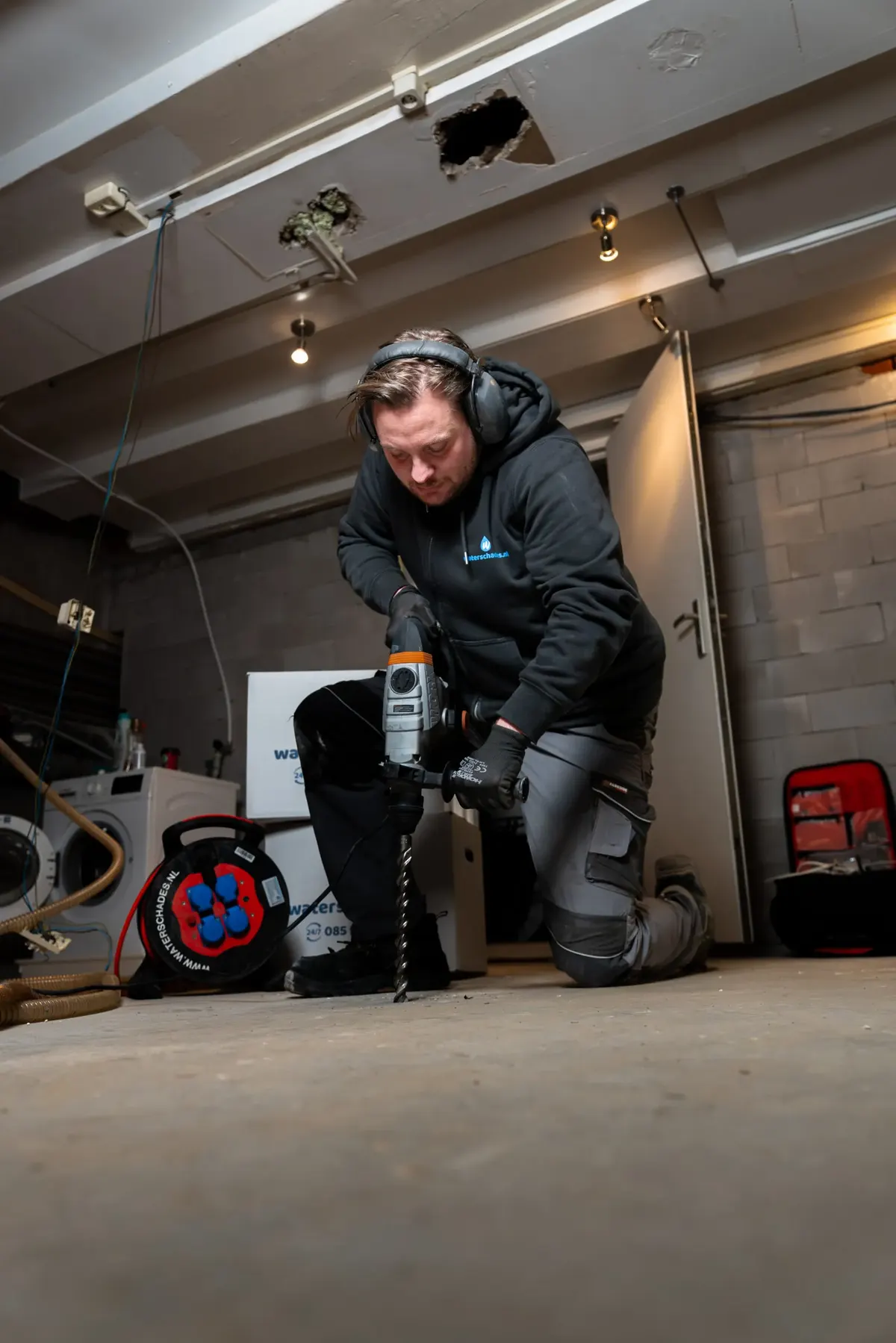 Medewerker van Waterschades.nl plaatst apparatuur in een gestripte ruimte voor het breekwerk