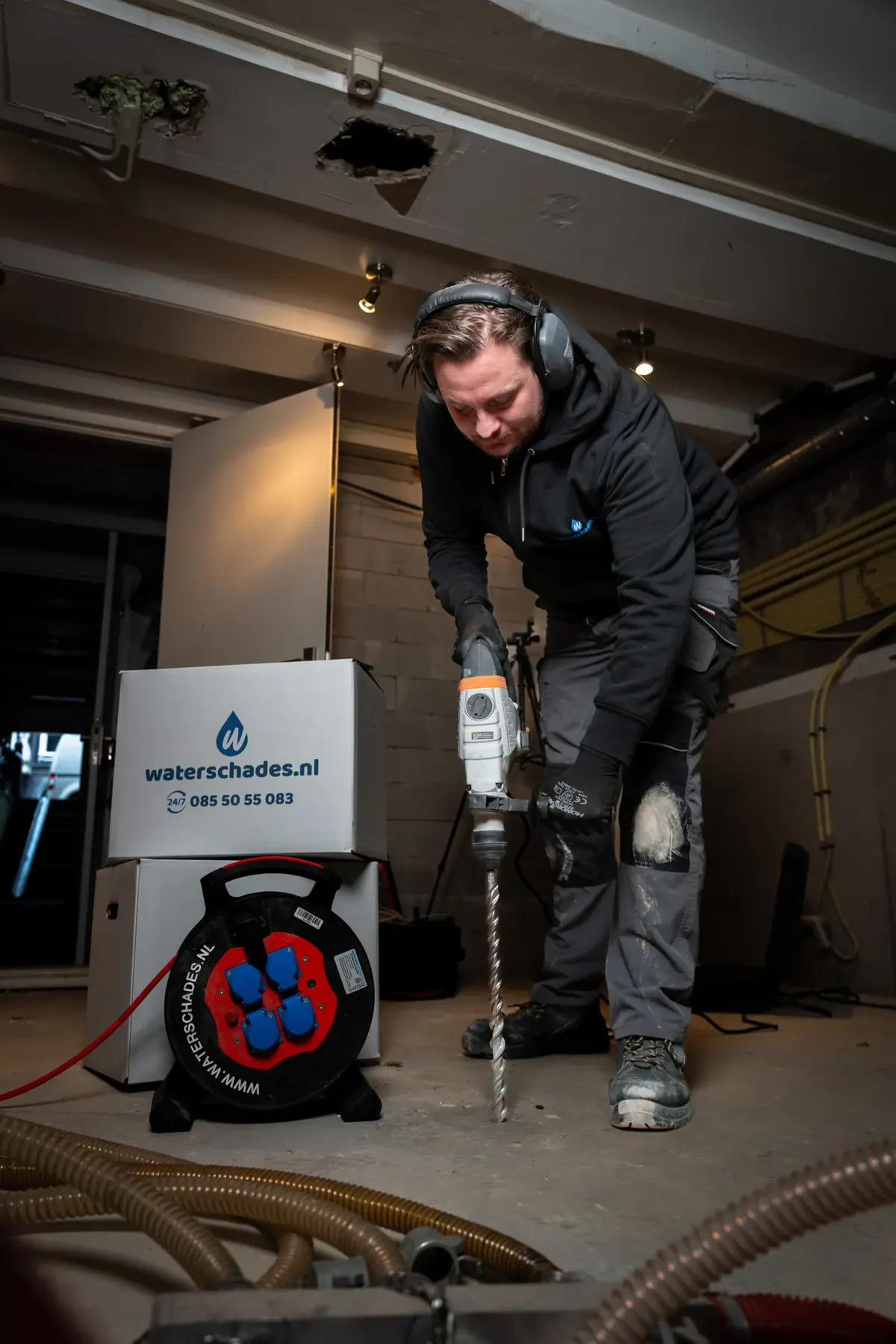 Medewerker van Waterschades.nl boort een vloer open om doorweekt materiaal te verwijderen