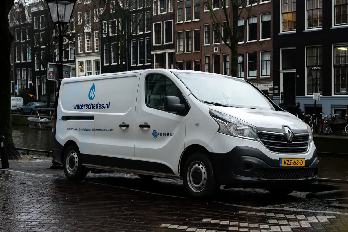 Servicebus van Waterschades.nl langs een Amsterdamse gracht tijdens een calamiteitenmelding