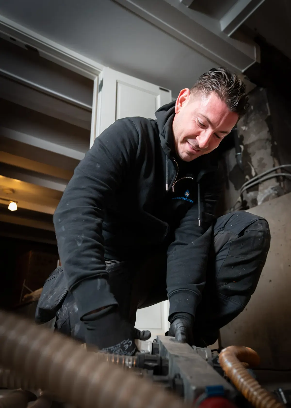 Specialist van Waterschades.nl legt afzuigslangen aan in een ruimte met waterschade